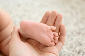 Woman holding cute small baby foot, closeup