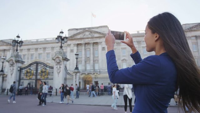 Woman taking picture of London tourist attraction on phone. 