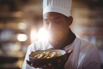 Close-up of chef with eyes closed smelling food 
