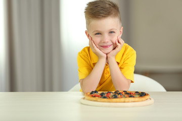 Cute boy with hot pizza at home