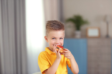 Cute boy eating pizza at home