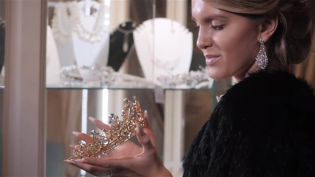 woman chooses bridal accessories in wedding boutique and wear crown with diamonds