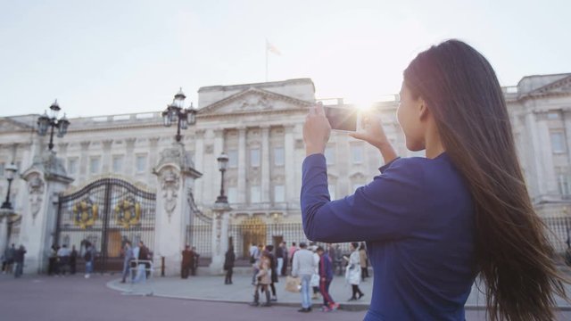 Woman taking picture of London tourist attraction on phone.