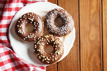 Plate with tasty donuts on wooden background