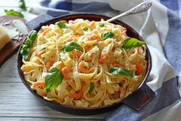 Pan with tasty alfredo pasta and napkin on wooden table