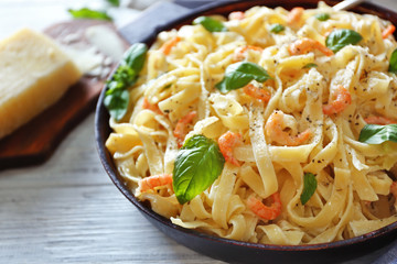 Pan with tasty alfredo pasta on wooden table