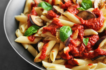 Pan with tasty macaroni, ketchup, eggplant slices and basil, close up view