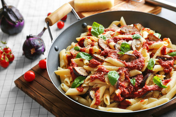 Pan with tasty macaroni, ketchup, basil and eggplant slices on grey table
