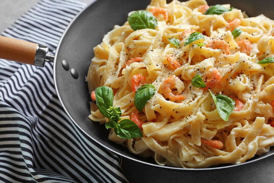 Pan with tasty alfredo pasta and napkin on table