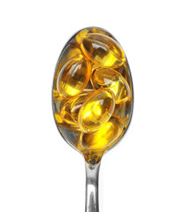 Capsules with cod liver oil in spoon isolated on white