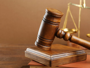 Judge's gavel and scales on brown background