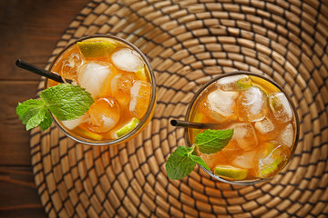 Glass of iced tea with lime slices and mint on wicker mat