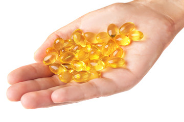 Fish oil pills in female hand on light background