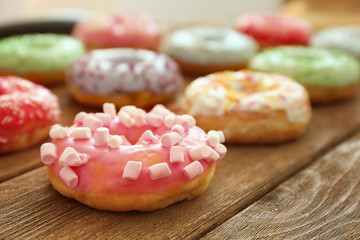 Tasty colorful donuts on wooden table, close up view