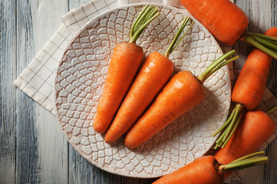 Plate with crunchy carrots on grey wooden table