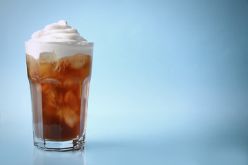 Glass of iced coffee with cream on blue background