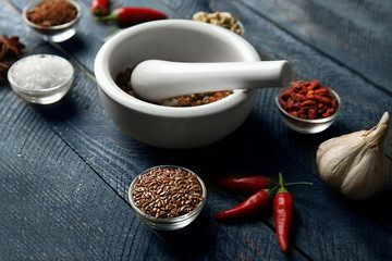 Composition with different spices and mortar on dark wooden background