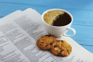 Fresh tasty coffee and newspaper on blue background