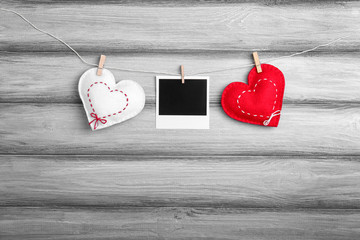Small soft hearts and photo card hanging on wooden background