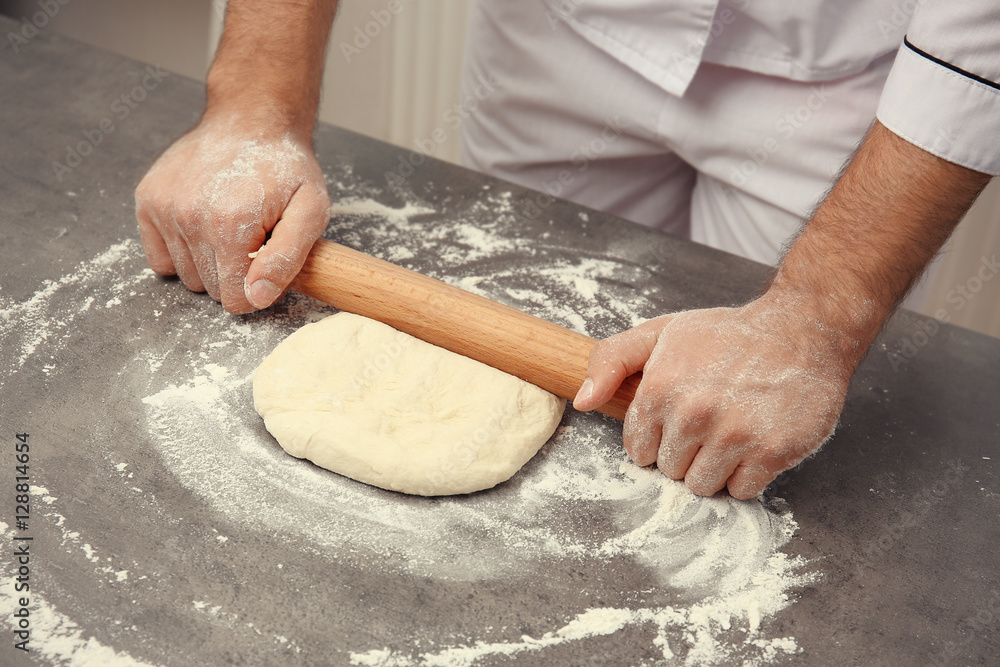 Wall mural Male hands preparing dough for pizza on table closeup