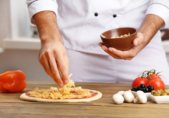 Male hands preparing pizza at wooden table closeup