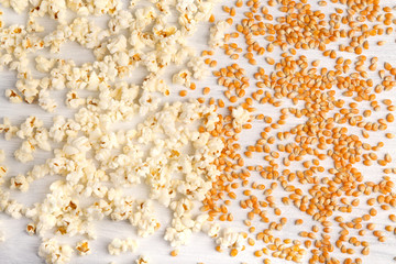 Corn grains with popcorn on white wooden background