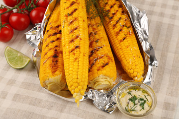 Grilled corns with cherry tomatoes and ingredients on table