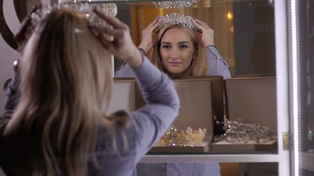woman chooses bridal accessories in wedding boutique and wear crown with diamonds