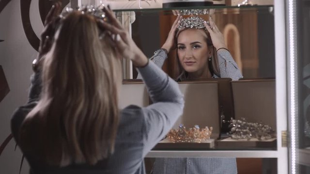 woman chooses bridal accessories in wedding boutique and wear crown with diamonds