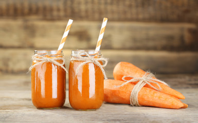 Fresh carrot smoothie and vegetables on wooden wall background