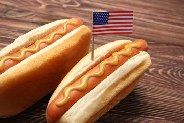 Hot dogs with mustard and small USA flag on wooden background