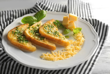 Plate with tasty garlic French bread slices and striped napkin