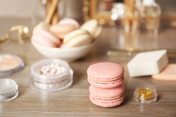 Tasty macaroons and beauty accessories on table