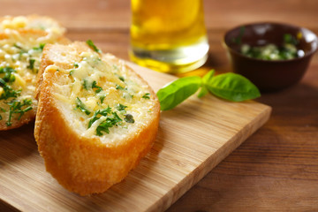 Tasty bread with garlic, cheese and herbs on kitchen table, close up
