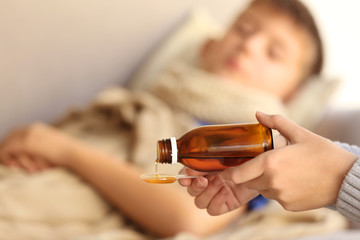 Woman pouring syrup for sick boy