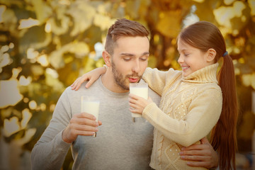 Father and daughter with glasses of fresh milk outdoor