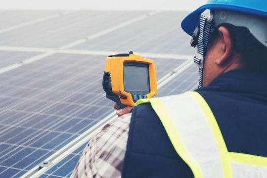 engineer or electrician working on  maintenance equipment at industry solar power;  engineer using thermal imager to check temperature heat of solar panel 
