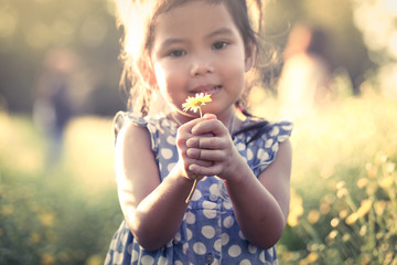 Child asian little girl holding flower in her hand in the garden