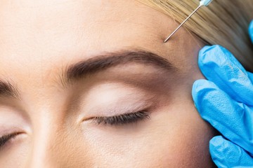 Woman receiving cosmetic injection on her forehead