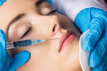 Woman receiving cosmetic injection on her lips