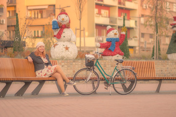 Young woman sitting bench, city decoration New Years Christmas