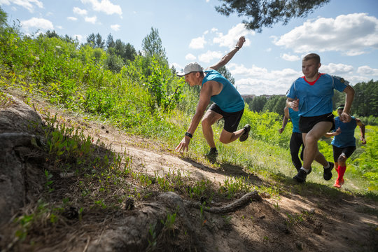 Trail running athletes crossing off road terrain at sunny day