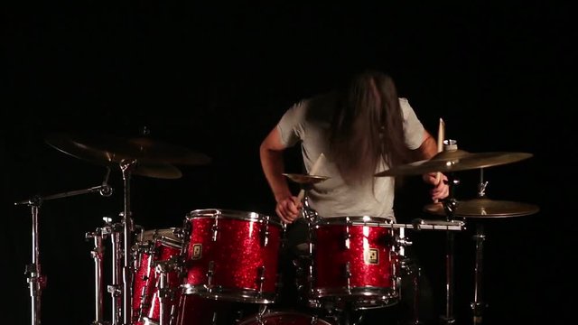 Drummer playing drums. Black background