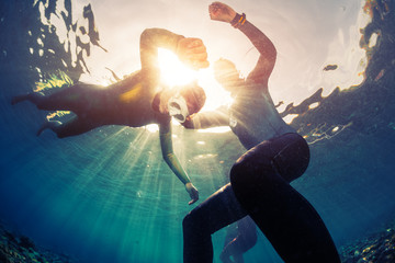 Underwater shot of the freedivers training static breath hold in shallow water of a calm bay. Coach...