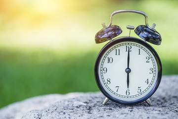 clock in the green nature background, retro bell clock time at 6 o'clock.