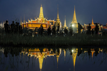 Naklejka premium BANGKOK, THAILAND - OCT 14, 2016: Wat Phra Kaew was reflected on water with people in black shirt. The royal procession transferring the body of the King, at the Grand Palace, Bangkok.