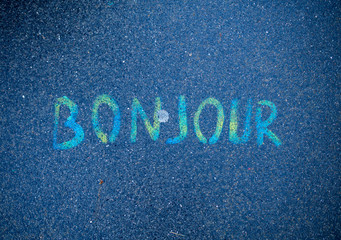 Bonjour written by colorful paints on street concrete floor