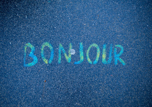 Bonjour written by colorful paints on street concrete floor