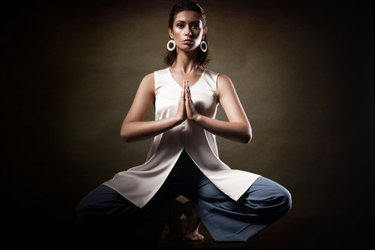 Stylish young athletic girl in fashionable clothes, showing yoga asanas in the studio. Beauty face and body health