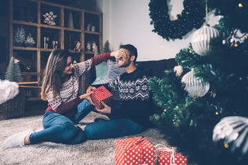Woman closing eyes to boyfriend giving present
